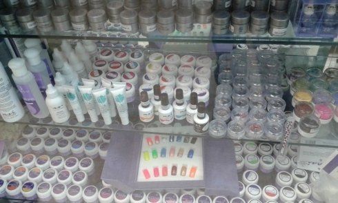 Prodotti per unghie in esposizione: vari gel, smalti e articoli decorativi in un ambiente di vendita al dettaglio.