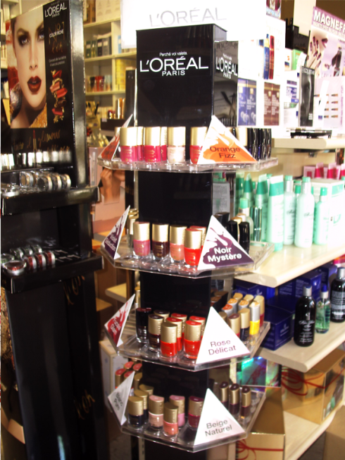 Espositore di smalti L'Oréal in un negozio; vari colori in un supporto rotante a più livelli.