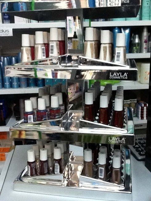 Espositore a tre livelli di flaconi di smalto Layla in vari colori, in un negozio.