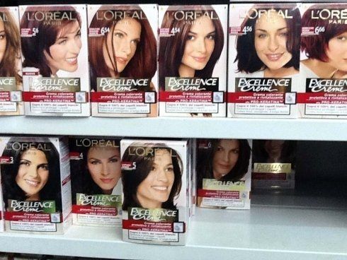 Scatole di tintura per capelli L'Oreal Excellence Crème sullo scaffale di un negozio, con diverse tonalità di colore per capelli.
