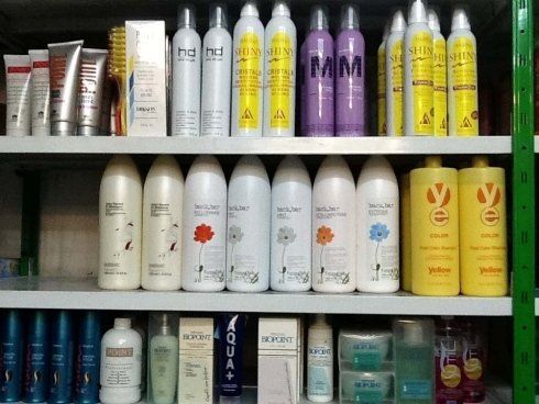 Scaffali pieni di vari prodotti per la cura dei capelli in un negozio.