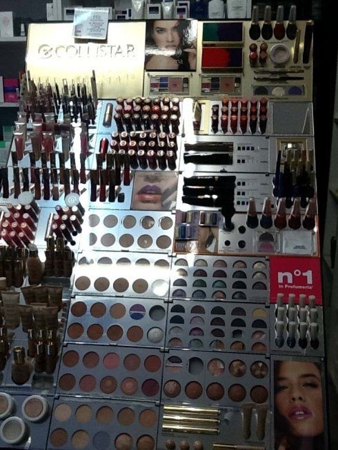 Espositore di cosmetici con rossetti, ombretti e altri prodotti per il trucco disposti su uno stand in un negozio.