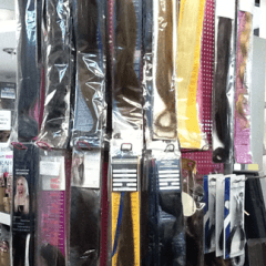 Extension per capelli esposte in un negozio, di vari colori e lunghezze, confezionate e appese.