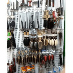 Esposizione di varie spazzole e pettini per capelli appesi a una parete espositiva di un negozio.