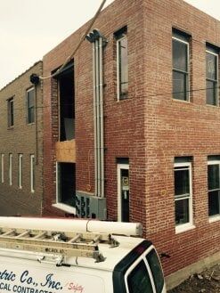 Brick industrial building with tall windows and a service truck in the foreground