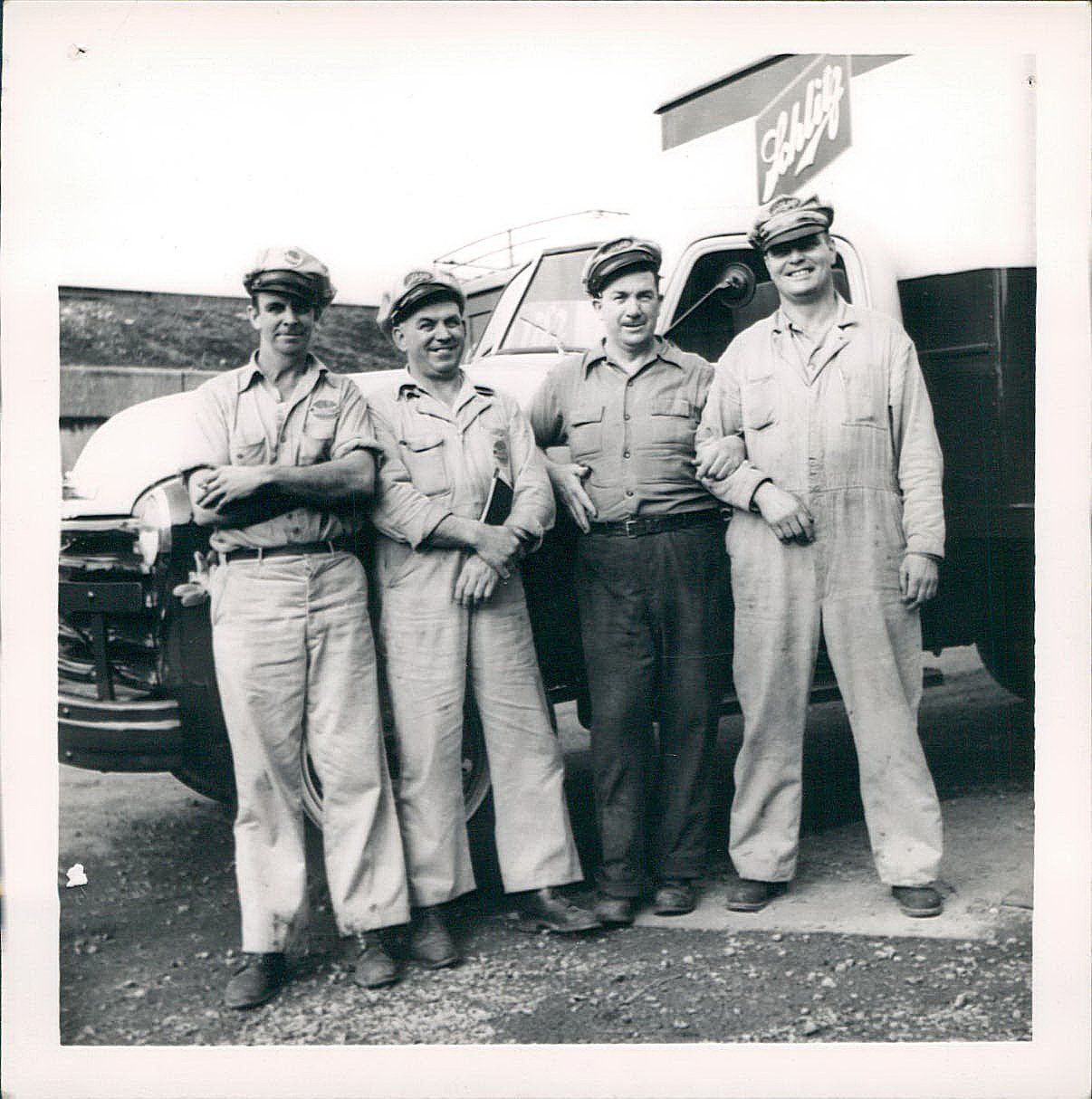 A group of men are posing for a photo in front of a truck that says ' sleigh ' on it