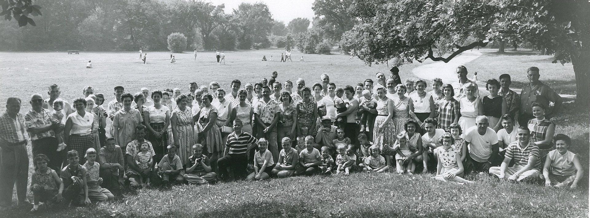 A black and white photo of a group of people sitting in the grass.