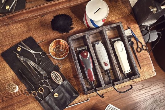 A barber 's tools are sitting on a wooden table.