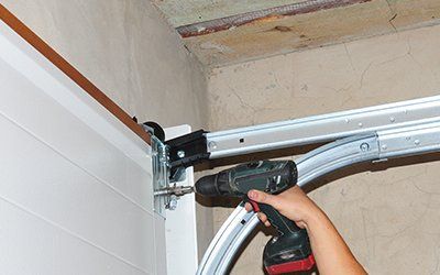 Garage Door Repair — Man Repairing Broken Garage Door in Converse,TX
