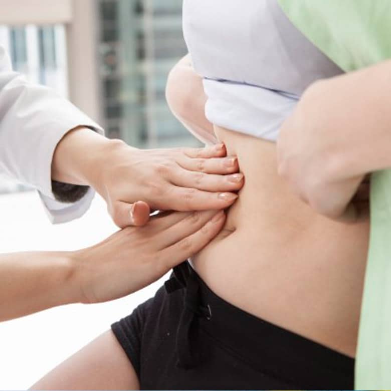 Médico realizando exame clínico abdominal em paciente para avaliação de condições do reto e intestino