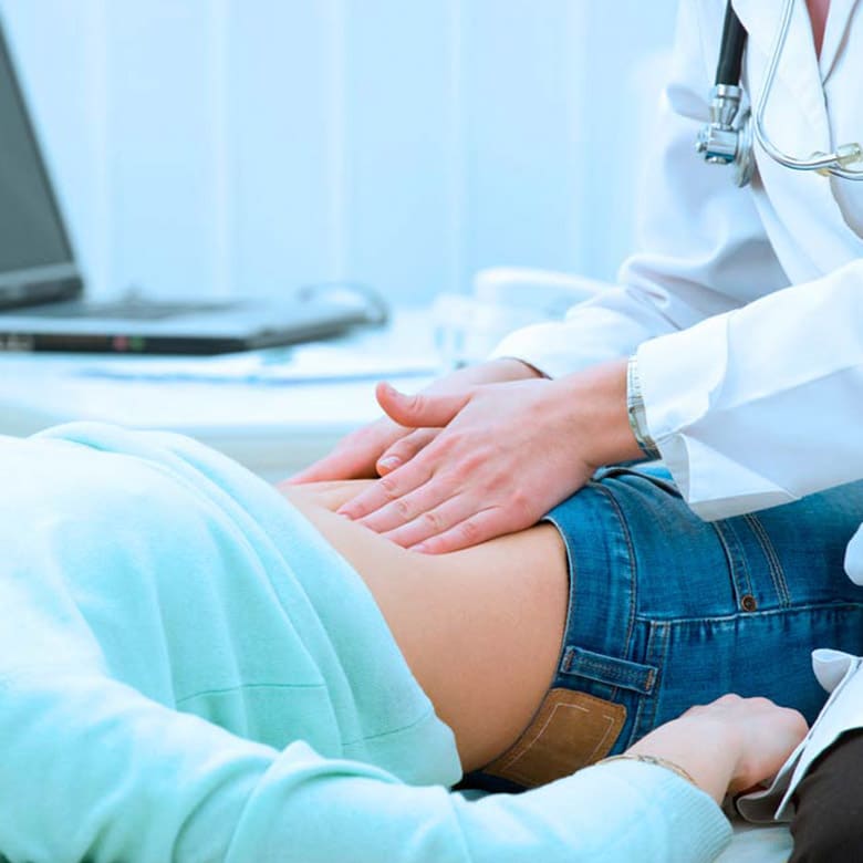 Médico gastroenterologista realizando exame clínico de palpação abdominal