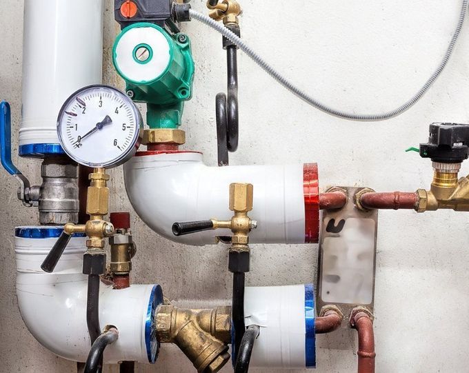 A close up of a heating system with pipes and gauges.