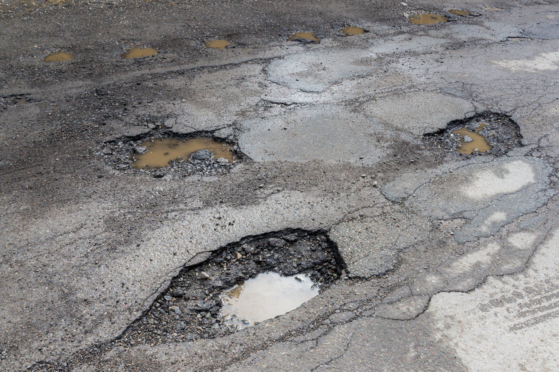 Asphalt Repair — Potholes On A Paved Road in Warsaw, IN Asphalt Repair — Potholes On A Paved Road in Warsaw, IN