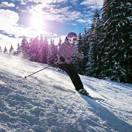 Skier descending snowy slope in mountains, sunny day.