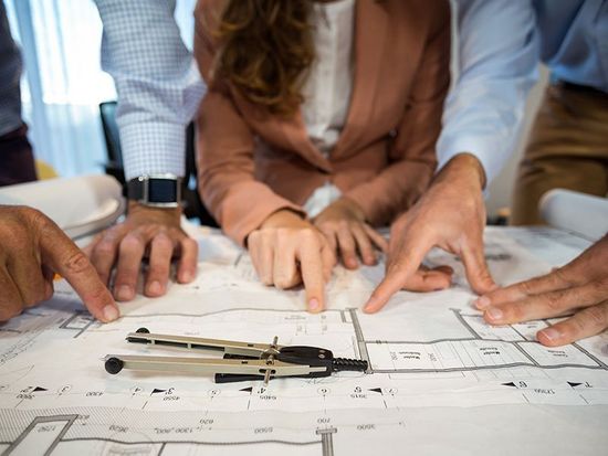 dei geomteri mentre lavorano su una pianta di un edificio