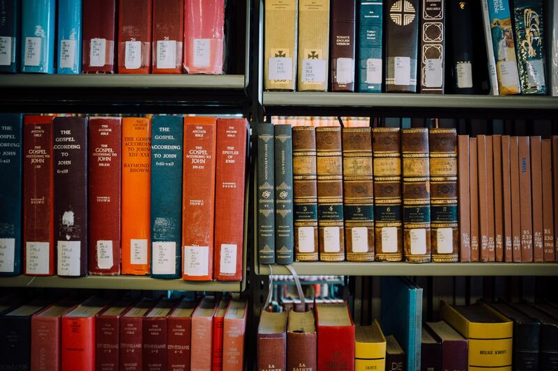 Three shelves filled with various colorful, leather-bound books in a library.