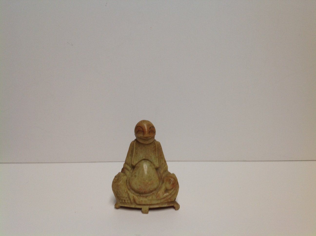 A small statue of a man sitting on a white surface.