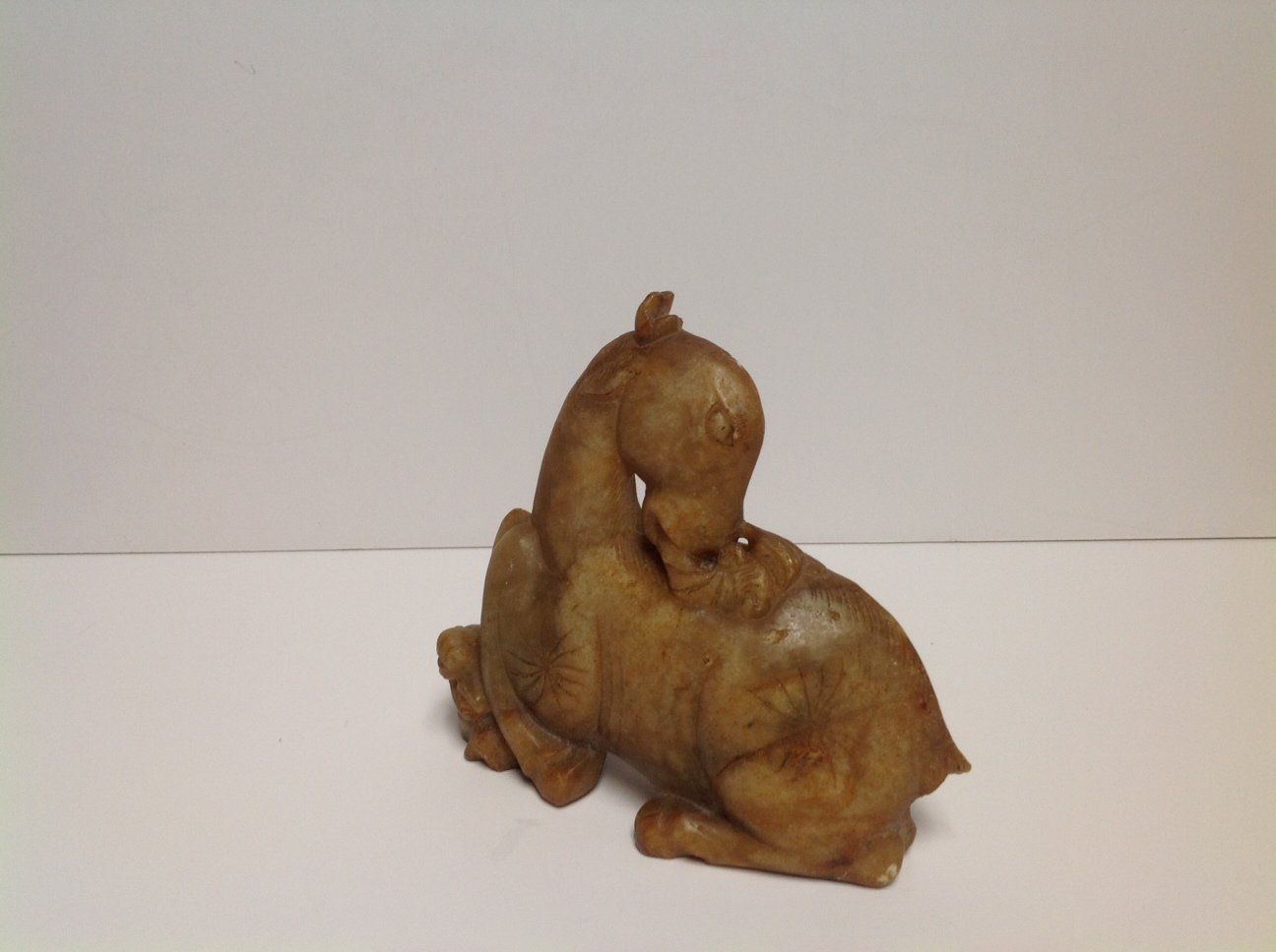 A statue of two camels sitting next to each other on a white surface.