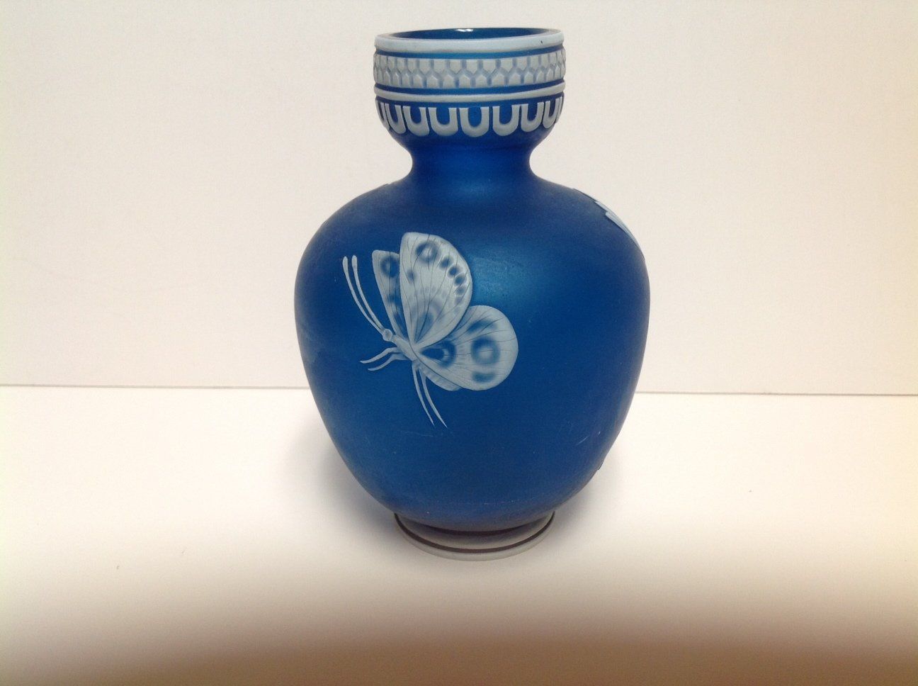 A blue vase with a white butterfly on it