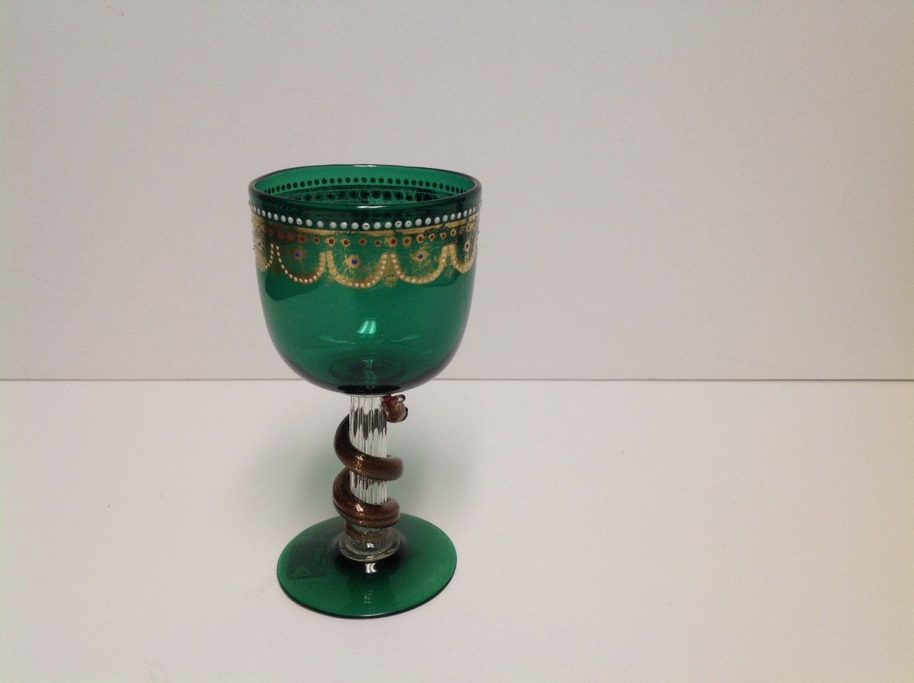 A green wine glass with a gold design on it