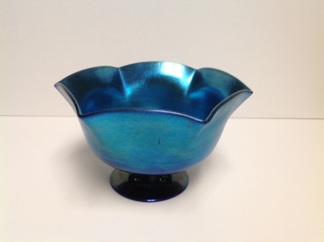 A blue bowl with a black base sits on a white surface