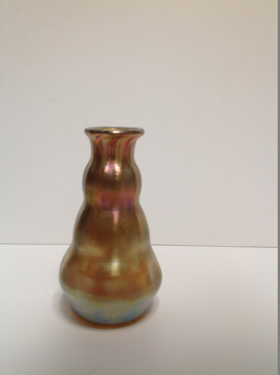 A small vase is sitting on a white surface.