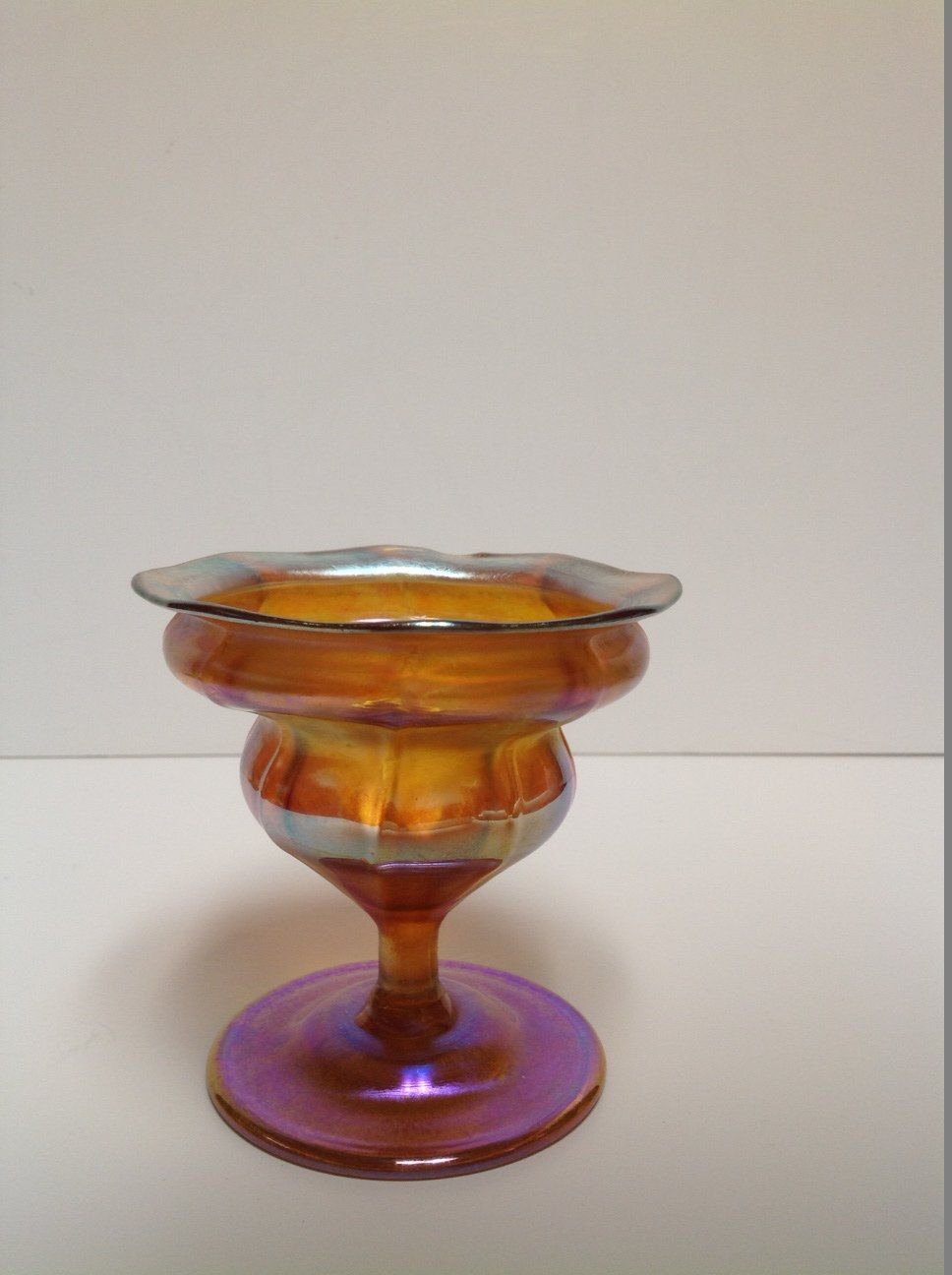A colorful glass vase is sitting on a white table.