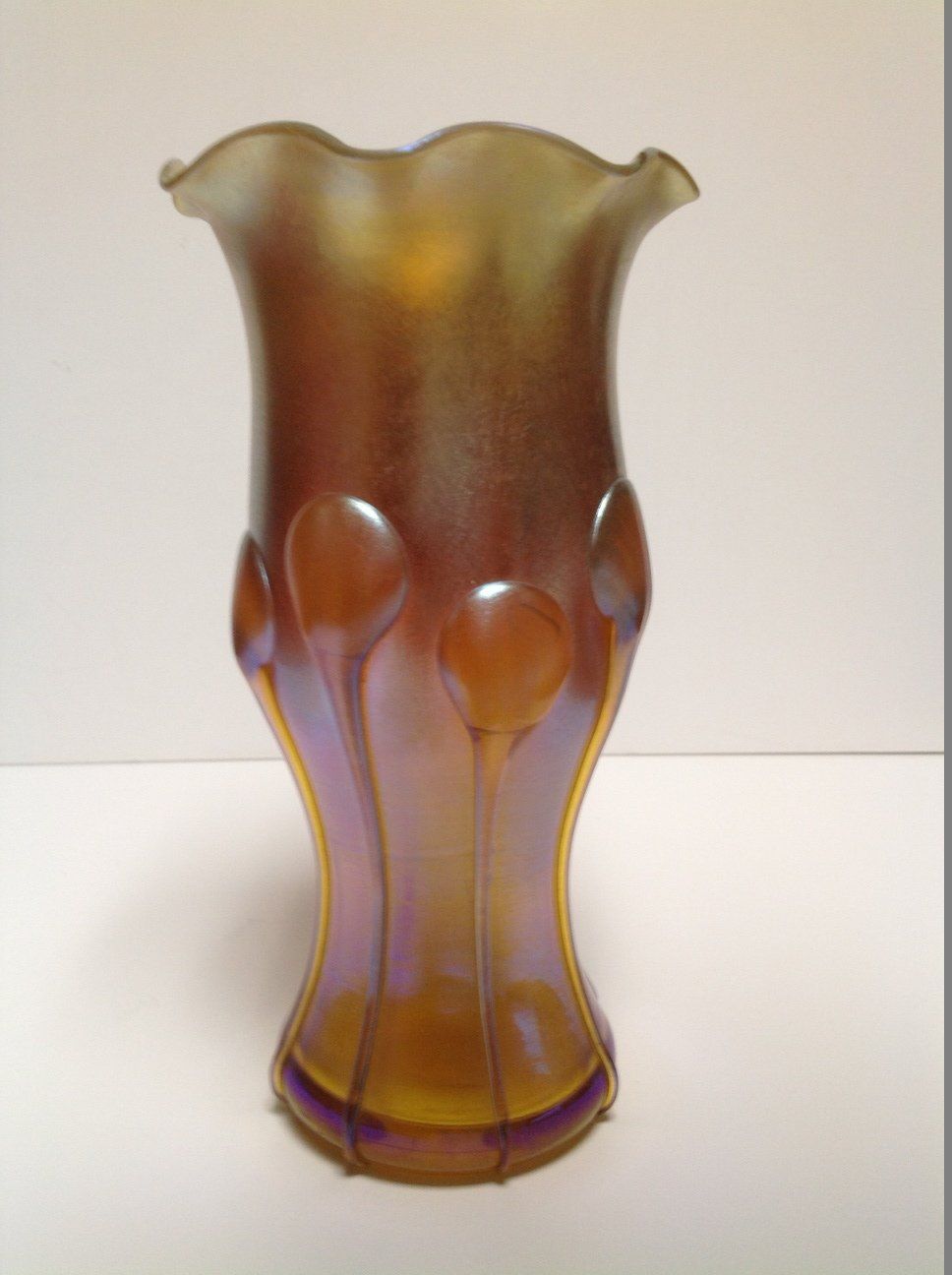 A colorful glass vase is sitting on a white surface