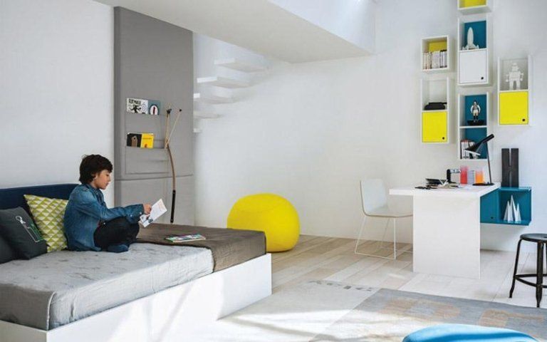 Persona seduta su un letto in una luminosa camera da letto moderna con dettagli gialli.
