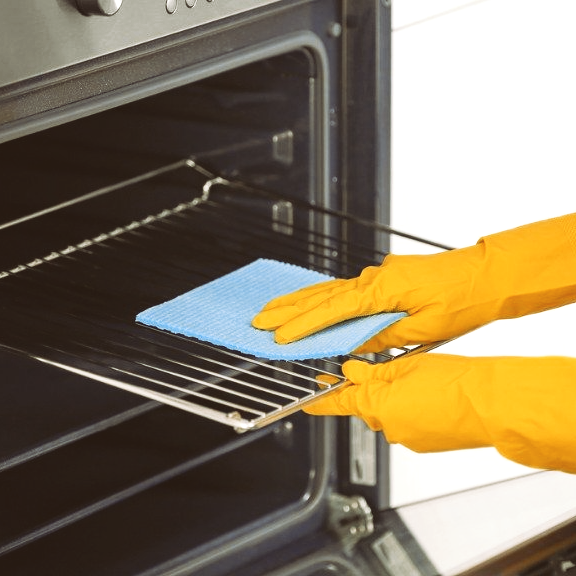 Gloved hands wipe an oven rack with a blue cloth inside a kitchen oven.
