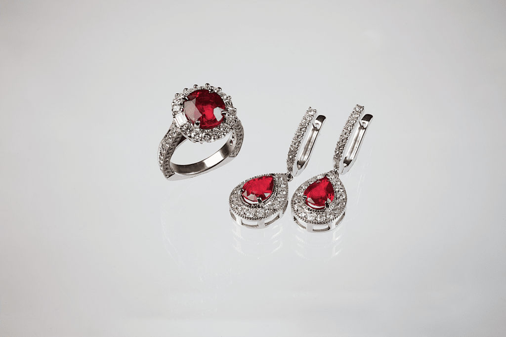 Ring and earrings set with ruby red center stones and surrounding white diamonds.