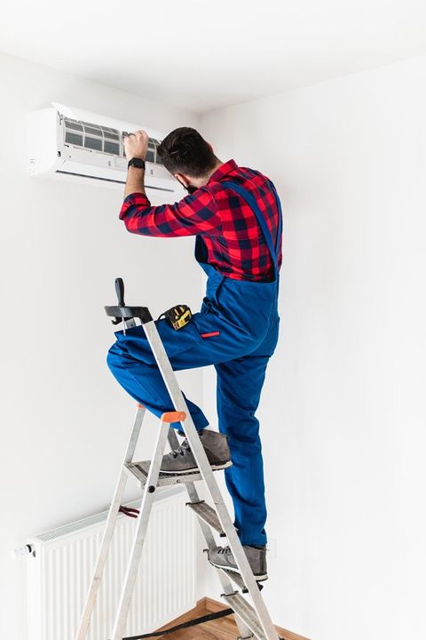 Man Changing Filter In Air Conditioner — Quakertown, PA — Lou The Plumber LLC Man Changing Filter In Air Conditioner — Quakertown, PA — Lou The Plumber LLC