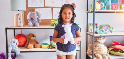 Beautiful toddler girl holding cute unicorn doll