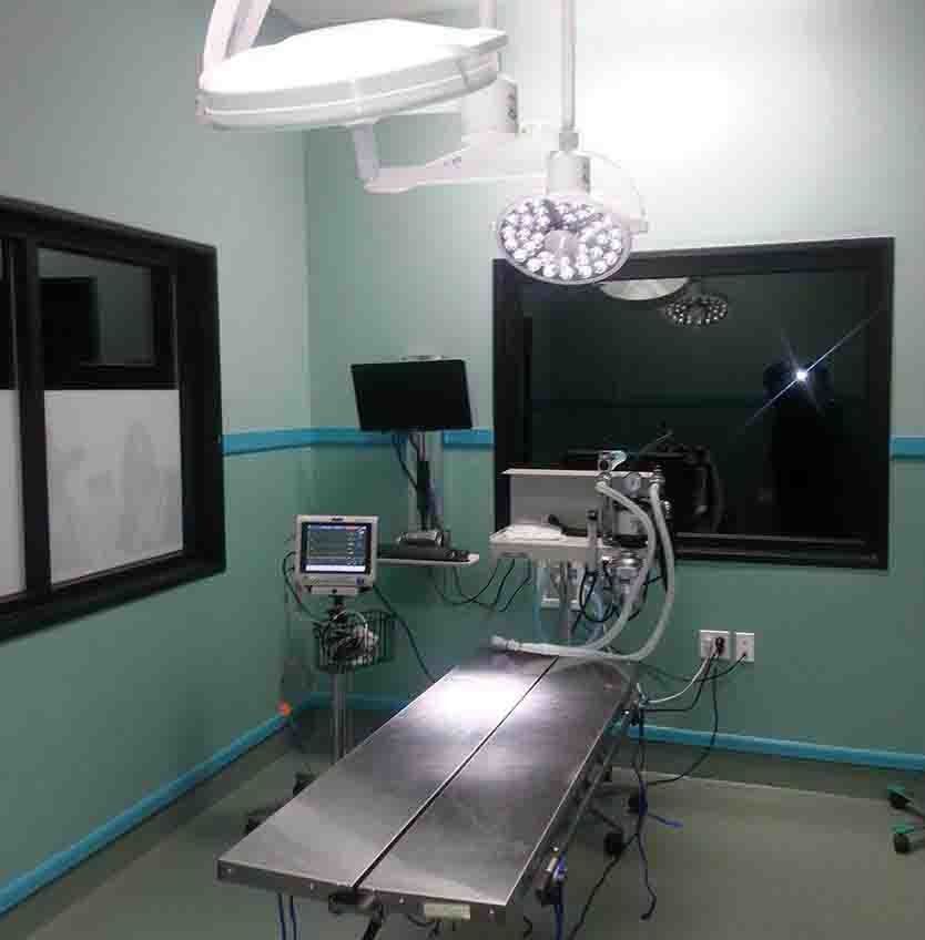 An operating room with surgical lights and an examination table; medical equipment present.