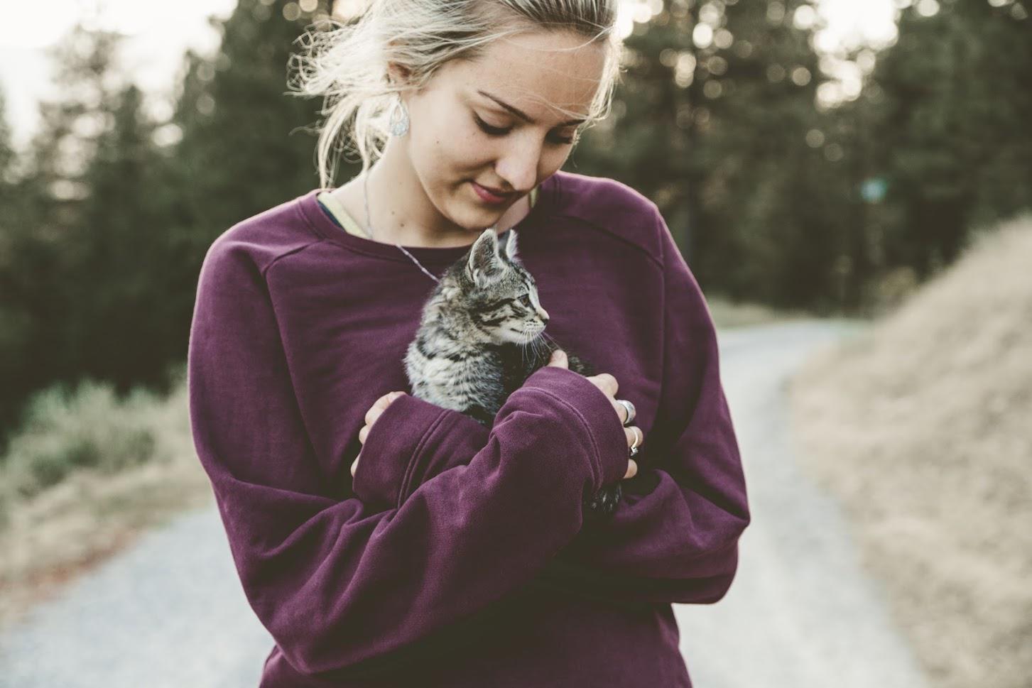 Lady Carrying A Cat — Seattle, WA — South Seattle Veterinary Hospital Woman holding a tabby cat close to her chest on a road; both are looking down.
