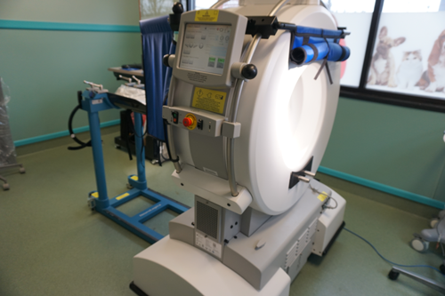 Medical device with a large, white circular opening and a control panel, in a room.