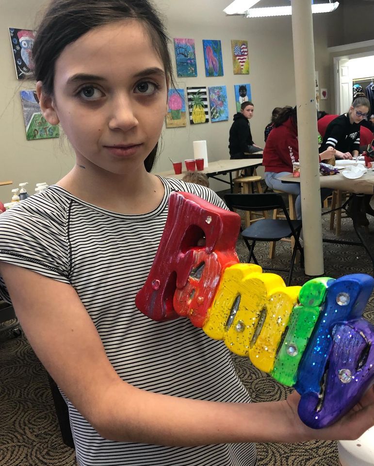 girl holding family woodwork art project