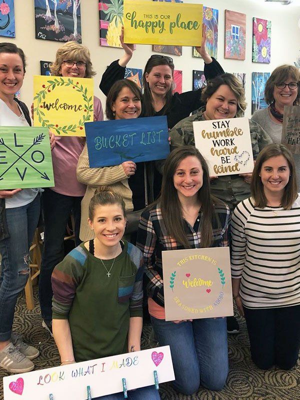 art class posing with their painted wooden signs