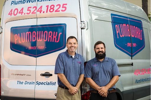 Get trained and work at the same time Two men stand in front of a PlumbWorks van. They both wear blue shirts and smile.