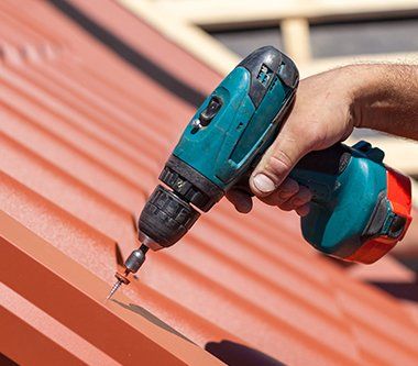 Worker on Roof with Electric Drill — Huntington Beach, CA — Accurate Roofing