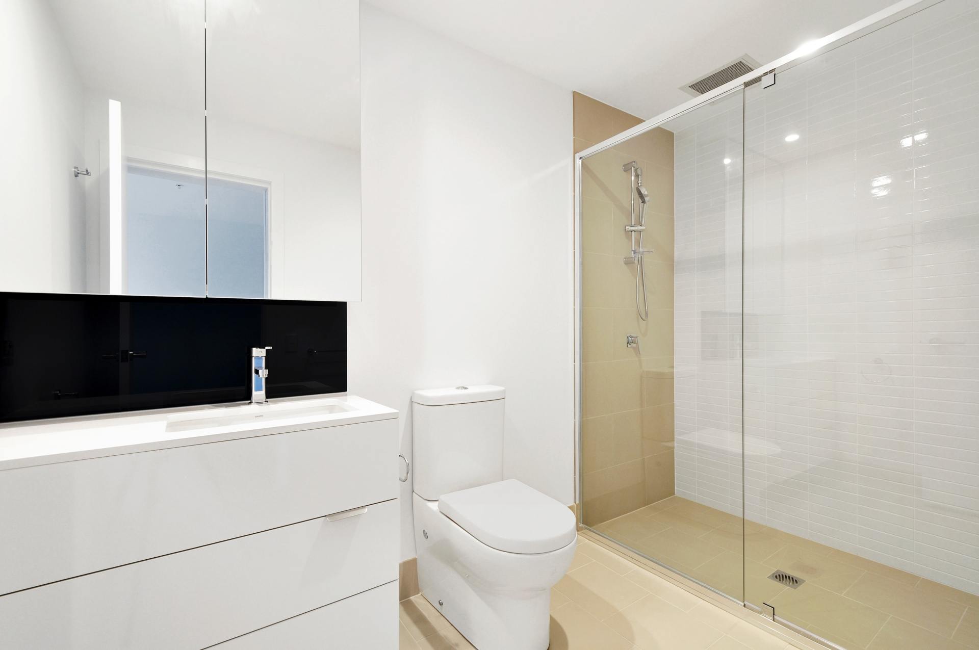 A bathroom with a toilet , sink and walk in shower.