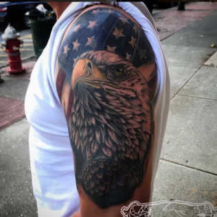 Close-up of an eagle tattoo on an arm with an American flag background
