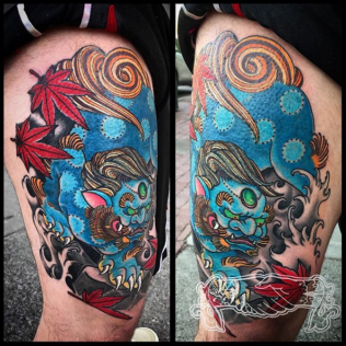 Two views of a colorful sleeve tattoo with blue skull, red leaves, and swirling orange-and-black design