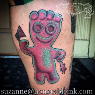 Pink cartoon tattoo of a smiling figure holding a black arrow, on skin