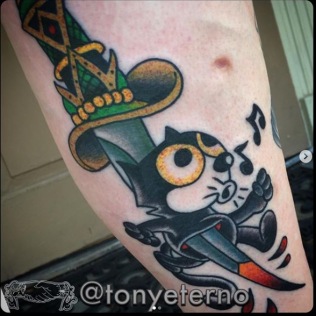 Cat tattoo with a sword and musical notes on a person’s leg