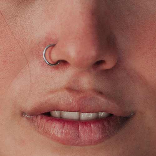 Close-up of a person’s nose and mouth with a silver nose ring and slightly parted lips