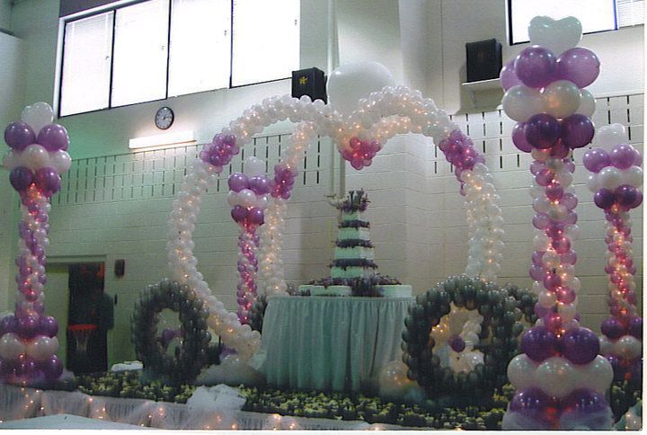 A beautiful cake at the center of an elegant balloon display with columns, low peak archways, and more.