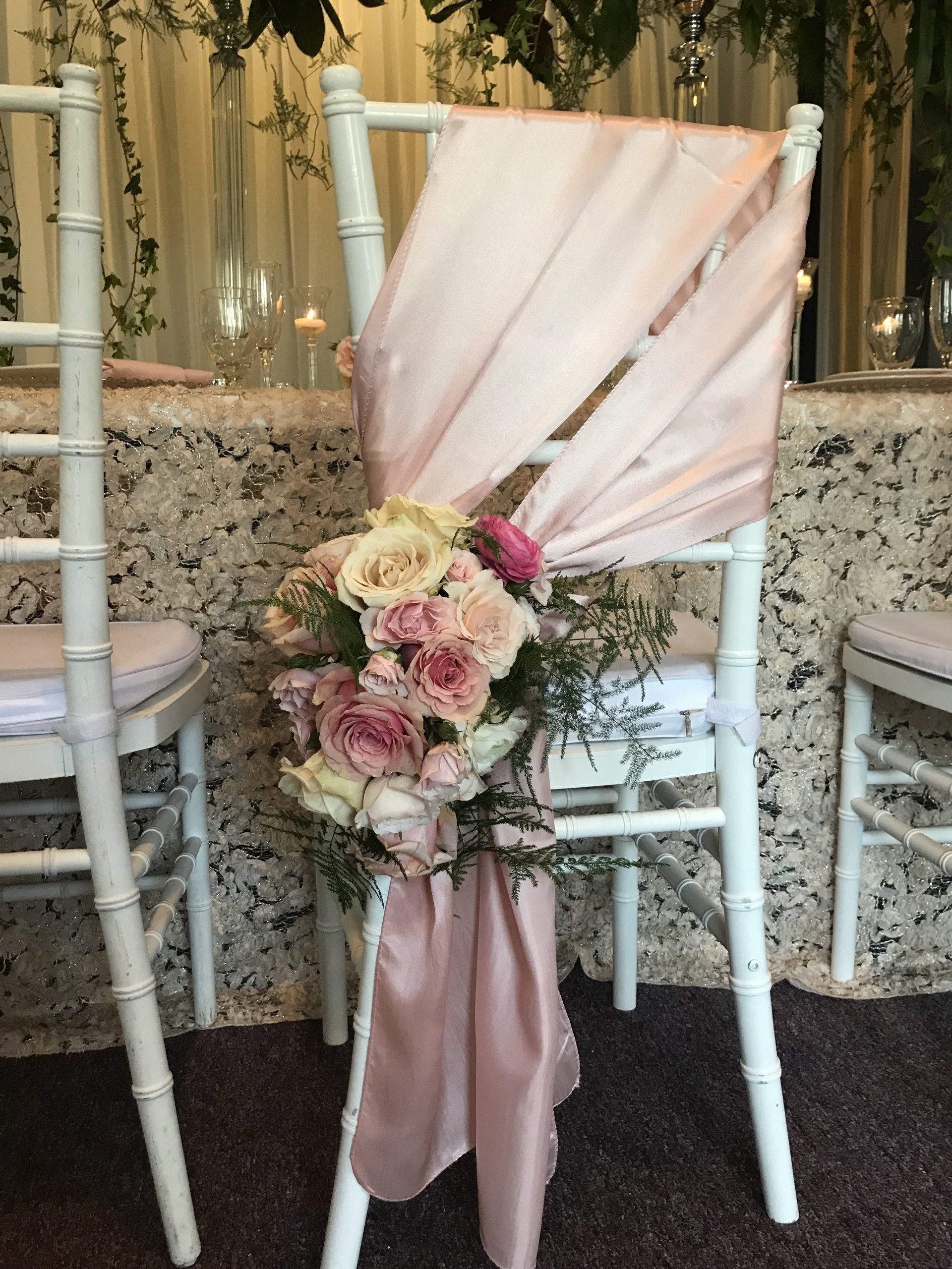 Chair decor with a satin cover and floral bouquet.