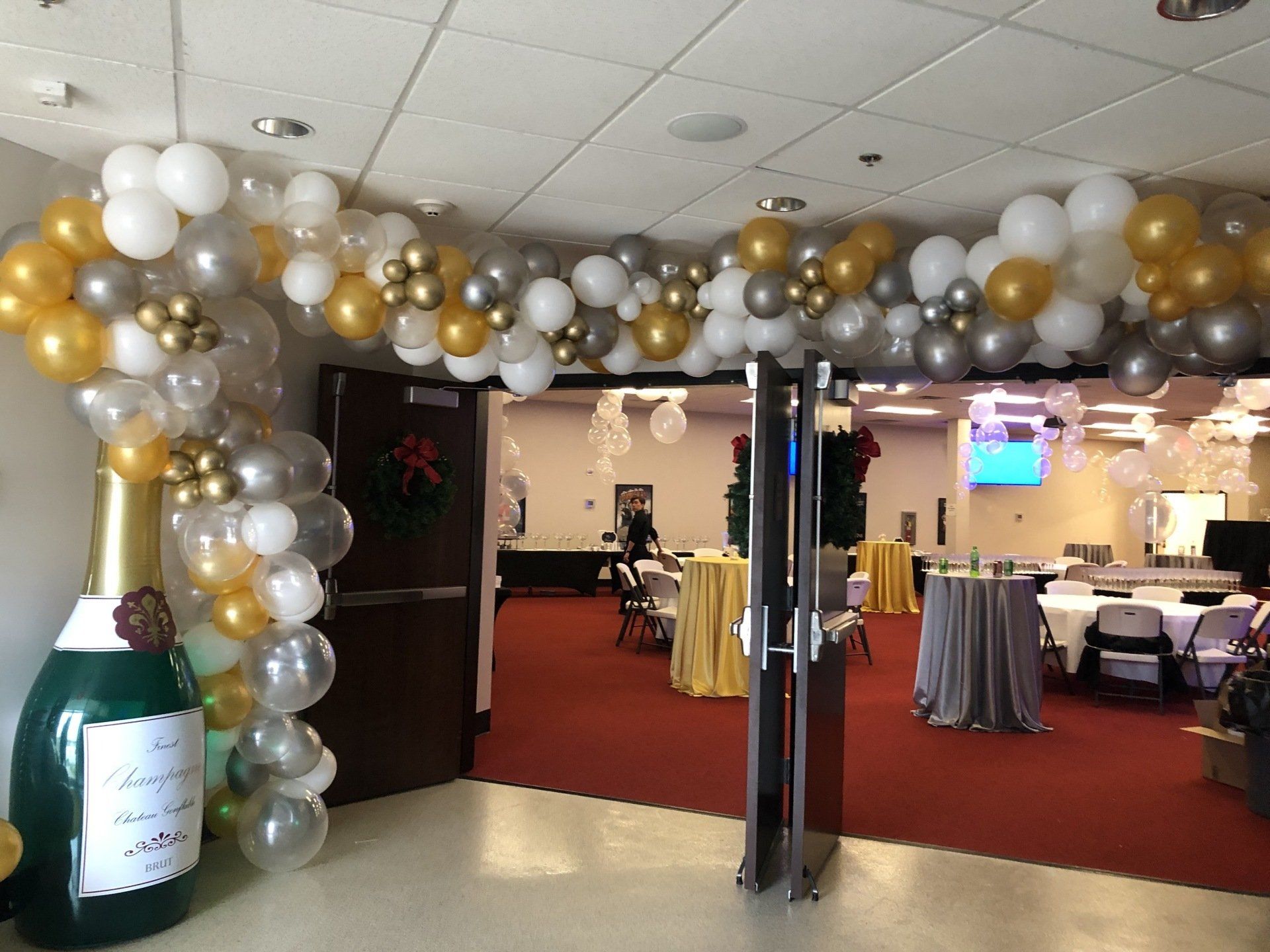 White and gold balloon arch framing doorway entrance for corporate or holiday event