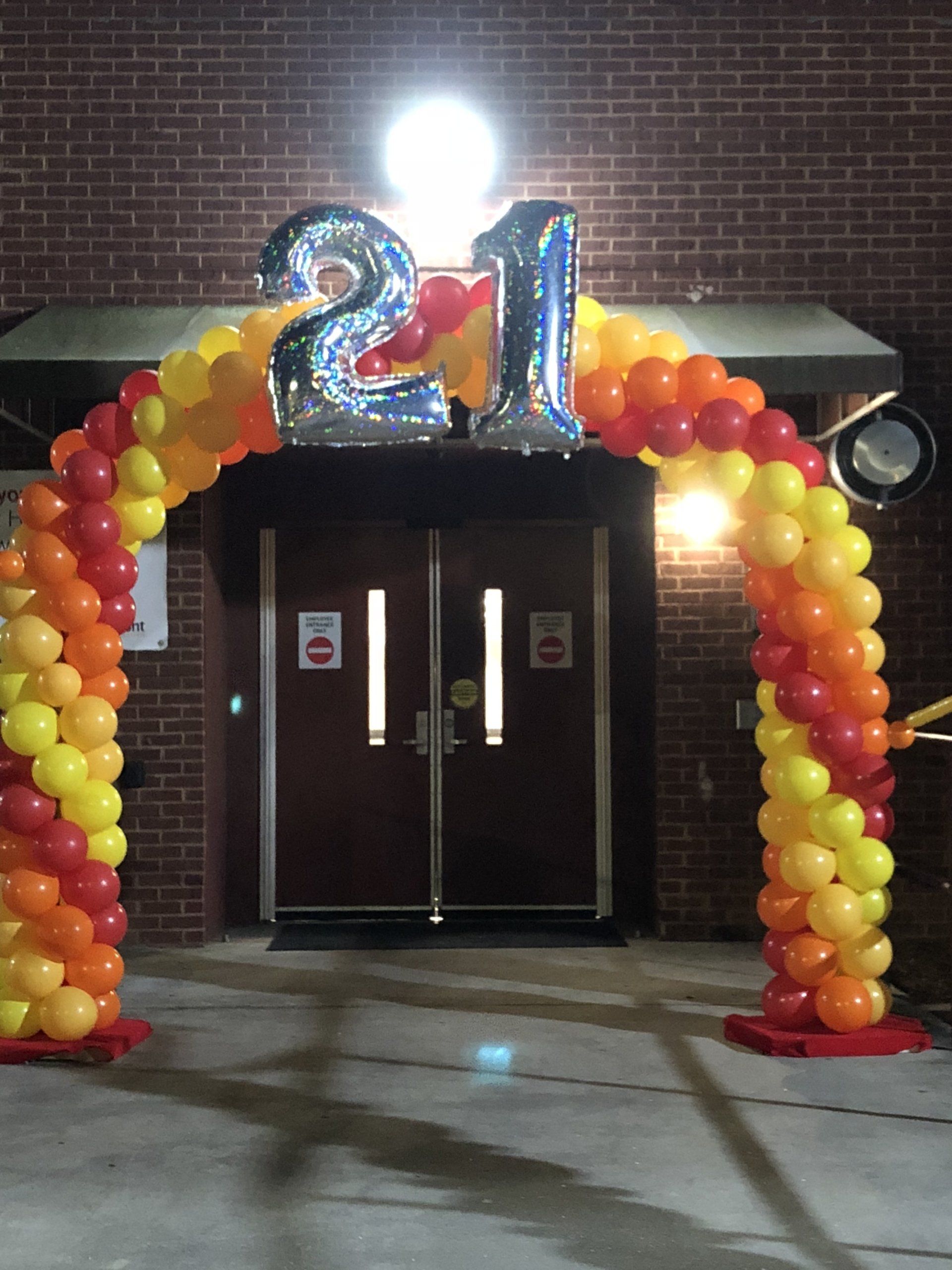 A welcoming arch with yellow, red and orange spiraled balloons with 